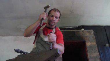 Demirci bir çelik örs üzerinde bir çekiç ile metalik bir gad isabet bir demirci Ukrayna'da karanlık bir demir demir gül yapmak için metalik bir keski çarpıcı. Muhteşem bir demir gül yapar.