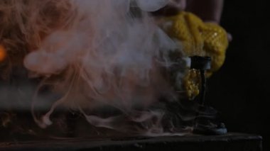 Dövme gül bir demirci atölyesinde kırmızı demir soğutmak için balmumu ile büyük bir yuvarlak tencereye koymak bir gül demir geleneksel demirci Heyecan verici görünümünde soğutmak için balmumu ile bir tencereye konur. Çok fazla duman yaratıyor.