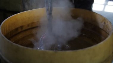 Metalik gül bir demirci atölyesinde erimiş demir soğutmak için balmumu ile balmumu büyük bir yuvarlak tencereye koymak bir gül demir eski bir atölye Spellful görünümünde soğutmak için balmumu ile bir tencereye yerleştirilir. Çok fazla buhar yapar..