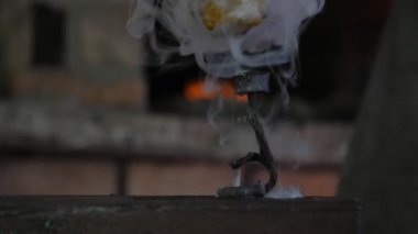 Loş bir demirci atölyesinde bir örs üzerine yerleştirilen dumaniçinde işlenmiş gül, geleneksel bir demirci nin iç mekanlarında bir örse yerleştirilen duman bukleleriyle kaplı dumanlı yapraklarıyla işlenmiş bir gülün muhteşem görünümü. 