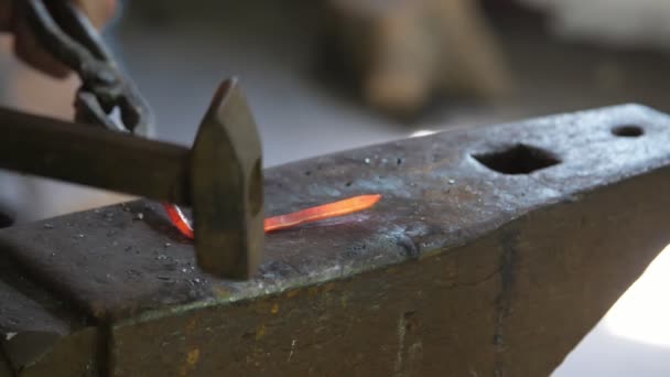 ウクライナの伝統的な鍛冶屋で赤い棒を打つエプロンの鍛冶屋は 若い鍛冶屋がハンマーで溶けた金属棒を打ち ウクライナの伝統的な鍛冶屋でそれを曲げるのビュー — ストック動画
