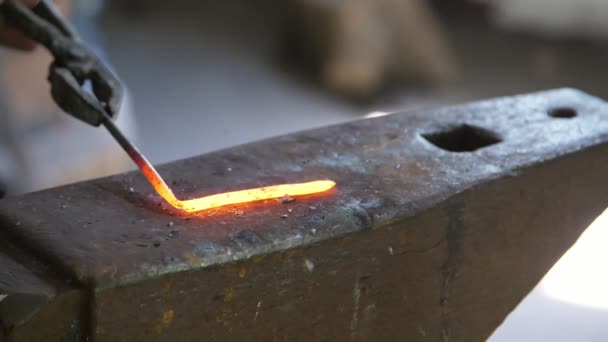 鍛冶師は ウクライナの薄暗い鍛冶屋で鉄のバラを作るために金属棒を曲げ 鍛冶屋が鋼のアンビルにハンマーで金属棒を打つ素晴らしい眺め 彼は棒を曲げてバラを作る — ストック動画