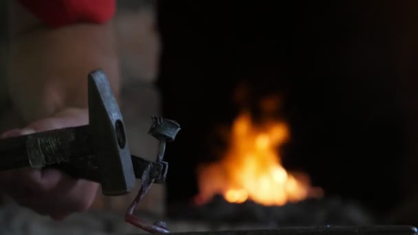 労働者は ウクライナの薄暗いスミシーで溶融金属棒を維持し スチールアンビルにハンマーで溶融金属棒を打つ鍛冶屋のクローズアップを打ちます 彼は鉄のバラを作る — ストック動画