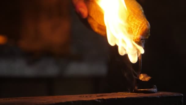 錬ローズは 鍛冶屋のワークショップで背景に光沢のある炉を持つ大きなアンビルに置かれた燃えるバラの鉄の見事な眺めで炎で覆われたスチールアンビルに置かれています — ストック動画