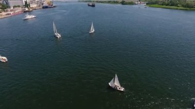 Güneşli bir günde Dnipro nehrine giden sportif yatların havadan çekilmiş görüntüsü Yazın güneşli bir günde Dnipro'da hareket eden çok sayıda beyaz yatın muhteşem kuş bakışı. Bir yarışa katılırlar. Gökyüzü gökseldir..
