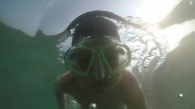 Gözlükle su altında yüzen ve yavaş çekimde eğlenen mutlu çocuk Yazın alanya sahilinde maskeyle dalan ve yaz aylarında alanya sahilinde aktif olarak yüzen mutlu bir çocuğun iyimser görünümü.