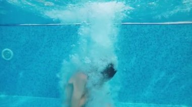 Slo-mo'da yüzme havuzunda sıçrama çeşmesi ile ilk dalış ayakları küçük çocuk şortlu aktif küçük bir çocuğun komik görünümü ilk ayak atlama ve slo-mo Türkiye'de bir wading havuzda neşeyle hareket sualtı vurdu
