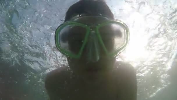 陽気な少年はゴーグルで水中を泳いで ゴーグルで水中に潜り スローモーションで夏のアランヤ海岸のカメラで微笑んでいる小さな男の子のスローモーションでカメラを見て — ストック動画