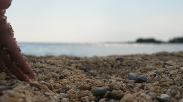 女性の手が掘り スローモーションで輝く夕日にアラーニャの海のビーチで砂や貝殻を取る女性の手の印象的なクローズアップで 日没時にトルコの海岸に砂を取ります — ストック動画