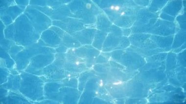 Slo-mo'da güneşli bir günde güneşli bir havuzda parıldayan gök suyu, Türkiye'de güneşli bir günde yüzme havuzunda oynayan altın ışınları ağı yla turkuaz suyun neşeli görünümünde 