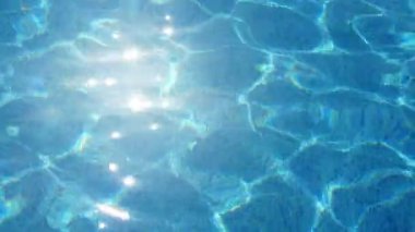 Slo-mo yaz güneşli bir günde modern bir yüzme havuzunun turkuaz suları kapsayan pırıl pırıl güneş yansıma lekeleri yavaş hareket Arty görünümünde bir wading banyo sallayarak mavi su parlak güneş yansıması