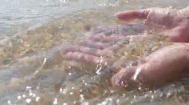 Slo-mo'da deniz kıyısında palmiyelerde kum ve kabuk tutan kadın elleri Yaz aylarında güneşli bir günde Karadeniz sahilinde kum, kabuk ve toparlama suyu tutan heyecan verici bir görünüm.