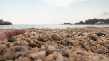 Slo-mo'da gün batımında deniz kıyısında kumla eğlenen ilham verici kadın elleri Yaz aylarında slo-mo'da gün batımında Akdeniz kıyısında kabukları ve kumları ile oynayan, kazan ve oynayan kadın ellerinin komik görünümü