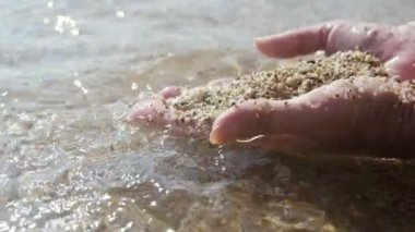 Yavaş çekimde alanya sahilinde kum tutan iki avuç içi, yaz aylarında güneşli bir güneşte deniz sahilinde ıslak kum ve kabukları kazarak ve oynayan iki erkek elinin harika görünümü