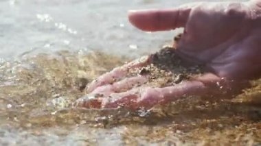 Alanya tatil beldesinde yaz aylarında bir erkek el kazma kum yavaş çekimde bir erkek el kazma ve yavaş çekimde yaz aylarında Akdeniz sahilinde sarı kum ve kabukları tutmak harika bir görünüm