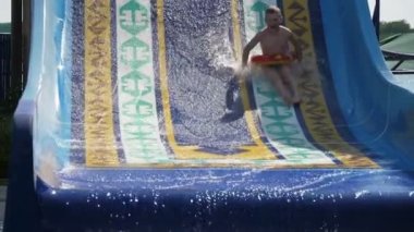 Çığlık atan çocuk ve kız, bir yüzük ve yaz aylarında yavaş hareket içinde Türkiye 'de bir Aquapark yamaçta düşen bir cıvıltı kız bir çığlık atan çocuğun Slo-Mo Cheery görünümü ile gülen yüzler ile dik bir su Tepesi aşağı kayar
