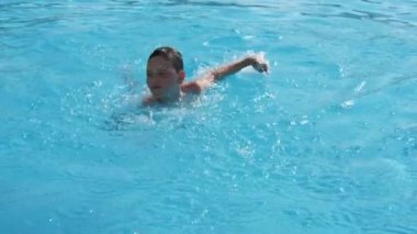 Slo-mo parlak suları ile yüzme havuzda mutlu küçük çocuk slo-mo köpüklü su suları ile bir kürek gölette serbest yüzme enerjik bir on yaşındaki çocuk neşeli görünümü