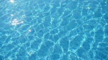 Slo-mo'da yüzme havuzunda oynayan crisscross ışınları ile neşeli su suları Türkiye'de temiz bir yüzme havuzunda şeffaf yeşilimsi-mavi suların arka plan görünümü yavaş çekimde