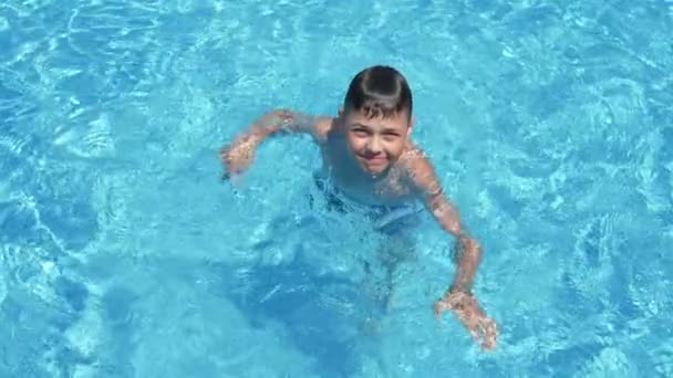 リラックスした小さな男の子は スローモでセレステの水と一緒に泳ぐ小さな男の子は スローモで輝くセレステの海とパドリング池で楽しく泳ぐエネルギッシュな10歳の少年の素晴らしい眺め — ストック動画