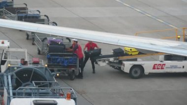 Antalya, Türkiye-14 Haziran 2019: büyük bir PASENGER uçaklarından Bagaj boşaltıyor ve yaz aylarında Alanya 'da küçük bir kamyonete sabit birçok Barrows koyarak iki askerin heyecan verici görünümü.