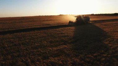Karanlıkta hava çekimi, koyu gün batımı içinde büyük tarım arazileri içinde hasat çiftinin harmanlandığı kuş bakışı Drone aynı hızda devam ediyor..
