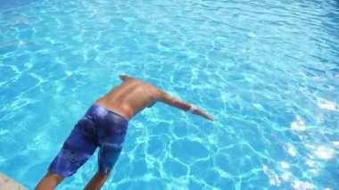 Atletik çocuk el ilk atlayarak havuz içinde turkuaz su ile Slo-Mo Sportive Brunet adam renkli şortlu bir asma gölet içinde Türkiye 'de güneş ışınları dolu turkuaz su ile ilk el atlama, Slo-Mo 