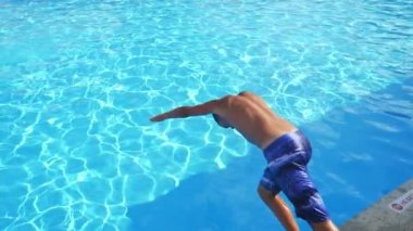 Spor çocuk el ilk yüzme havuzunda Celeste su ile havuz içinde Slo-Mo Athletic Brunet adam renkli şortlu ilk el atlayarak bir asma gölet, Celeste su ile Türkiye 'de güneş ışınları dolu Slo-Mo 