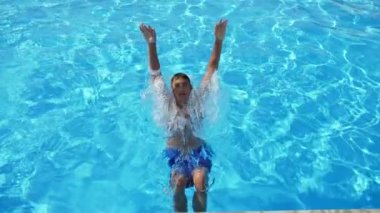 Sportive çocuk bir yüzme gölet frenlemek ve geri Slo-Mo onun sırt üzerinde hareketli bir atletik çocuk çok renkli şort bir Wading gölet frenlemek ve yavaş hareket yaz aylarında arka yüzme kapalı tekme