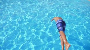 Akıllı adam eller ilk yüzme havuzunda açık mavi su ile Slo-Mo Cheery Brunet adam renkli şortlu ilk el atlayan bir gölet içinde güneş ışınları ile delinmiş açık mavi su ile Türkiye 'de Slo-Mo 