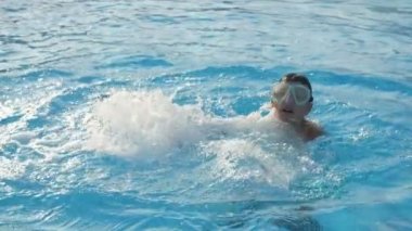 Bir maske içinde Cheery çocuk atlama ve Slo-Mo küçük bir çocuk sıçrama ve Slo-Mo yaz aylarında gün batımı Karadeniz sularında elleri ile çevreleme hareketleri yapma komik görünümünde gün batımı dalgalar içinde daire yapma