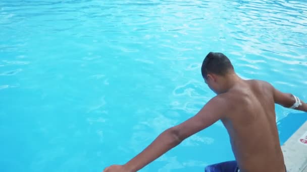 好奇的男孩跳像麻雀在戏水与绿松石水在Slo Mo活跃布鲁内特的家伙在五颜六色的短裤跳手首先在游泳池与塞莱斯特水充满阳光在土耳其在Slo — 图库视频影像