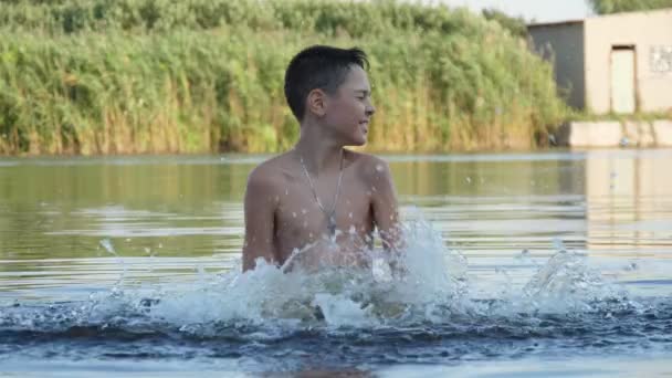 Jolly Mały Chłopak Stoi Klepiąc Wody Rozpryskiwania Wody Jeziora Zwolnionym — Wideo stockowe