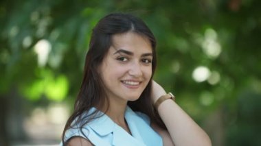 Güzel kız gülümseyen ve Slo-Mo yaz aylarında oyun etrafında başını dönüm uzun gevşek saç nazik gülümseyen ve Slo-Mo yaz aylarında yeşil bir sokakta parlak gözleri ile başını dönüm tatlı bir esmer kız muhteşem görünümü