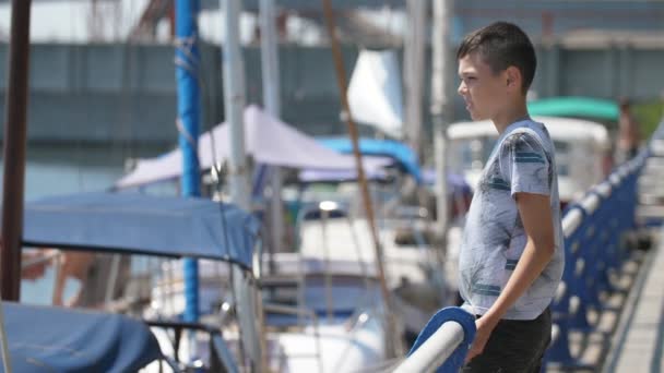 Garçon Ludique Debout Tenant Les Mains Courantes Regardant Les Yachts — Video