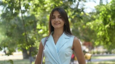 Zarif kız ayakta ve gizemli yeşil parkta yaz aylarında neşeli gülümseyen uzun gevşek saç ayakta ve yavaş hareket yaz aylarında yeşil bir parkta bir oynak dişlek gülümseme veren tatlı bir esmer kız Splendid Pan görünümü