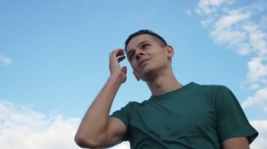 Cheery adam ayakta ve SLO-MO içinde Celeste gökyüzü altında sırayla saçlarını koyarak bir gülümseyen genç esmer adam sırayla ayakta ve Slo-Mo Celeste gökyüzü altında Karadeniz sularında zevk onun sallayarak saç koyarak görünümünü aşağı çarpıcı