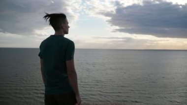 İlham genç adam ayakta ve bir T-shirt ve siyah pantolon ayakta ve Slo-Mo yaz aylarında Karadeniz sularında ilham alma saç sallayarak mutlu bir genç adam Slo-Mo duygusal geri Pan siyah deniz sularında bakıyor