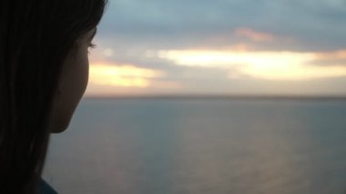 Uzun kirpik ve gevşek saç siyah deniz görünümlü güzel bir kız romantik bir genç esmer kız güzel profili sevimli siyah deniz dalgaları manzara yaz aylarında renkli günbatımı içinde Slo-Mo  