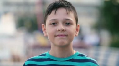 Mutlu brunet çocuk ayakta ve slo-mo slo-mo mürettebat saç kesimi ile küçük brunet çocuk iyimser portre dnipro seti üzerinde neşeli gülümseyen ayakta ve slo-mo yaz güneşli bir günde Dnipro seti üzerinde mutlu bir şekilde gülümseyerek