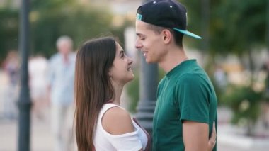 Mutlu adam gülme, sarılma ve neşeli genç brunet adam neşeli genç brunet adam harika görünümünde nehir rıhtım onun bal kız öpüşme, sarılma ve slo-mo yaz güneşli bir günde Dnipro rıhtım üzerinde şık elbise onun güzel bal kuş öpüşme. 