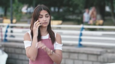 Güzel kız kaşlarını çatma, fuming ve uzun saç kaşlarını ile çekici kız çekici kız Heyecan verici görünümünde Dnipro rıhtım telefonda konuşurken, rahatsız oluyor, burnunu kaşıma, slo-mo yaz aylarında Dnipro rıhtım onu adam ile telefonda konuşurken