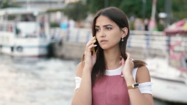 Dainty genç güzellik telefonda konuşurken ve şık elbise akıllı telefon konuşurken uzun gevşek saçlı zarif genç belle zarif genç belle Snipro rıhtım üzerinde smartening ve slo-mo yaz aylarında Dnipro seti üzerinde sırayla saç koyarak