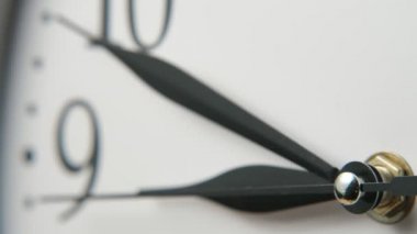 Geleneksel beyaz saat yüzünün on dakika ile dokuz etkileyici closeup gösteren üç keskin siyah elleri ile beyaz saat yüzü üç ok şeklinde siyah elleri hareket ile askew yerleştirilir, ölçme ve dokuz on dakika işaret.