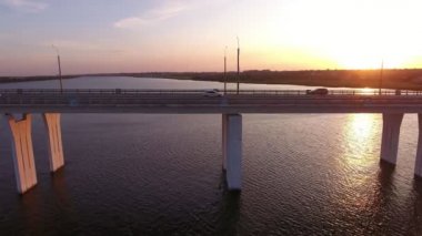 Yaz aylarında parlayan gün batımında Dnipro kapsayan günümüz köprüsühavadan çekilmiş Hareketli drone hareketli araba ile Dnipro üzerinde kübik beton sütunlar üzerinde yüce bir köprü Amazing kuş bakışı görünümü yaz aylarında sanatsal günbatımında kenara yerleştirilen hareketsiz drone bir kenara yerleştirilir