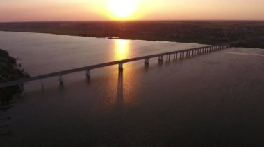 Yaz aylarında pırıl pırıl günbatımında Dnipro kapsayan muhteşem köprü havadan çekim Yaz aylarında altın bir güneş yolu ile göz kamaştırıcı günbatımında hareketli arabalar ve kamyonlar ile Dnipro üzerinde kübik beton sütunlar üzerinde büyük bir köprü güzel kuş bakışı görünümü
