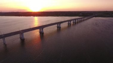 Yaz aylarında güzel bir gün batımında Dnipro üzerinde uzanmış bir köprü havadan çekim Yeşil bankalar ile Dnipro nehri üzerinde uzak modern köprü Muhteşem kuş bakışı görünümü, sürüş araba ve yaz aylarında güneş yolu ile gün batımında köpüklü su