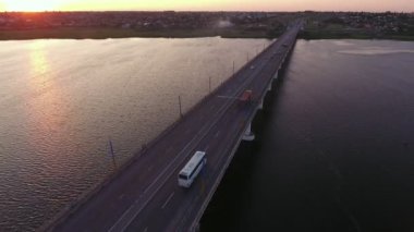 Yaz aylarında rüya gibi bir gün batımında Dnipro üzerinde lanky köprü havadan çekim Yeşil bankalar ile Dnipro nehri üzerinde yükselen modern bir köprü Amazing kuş bakışı görünümü, araba sürme ve yaz aylarında çok renkli gün batımında parlayan su