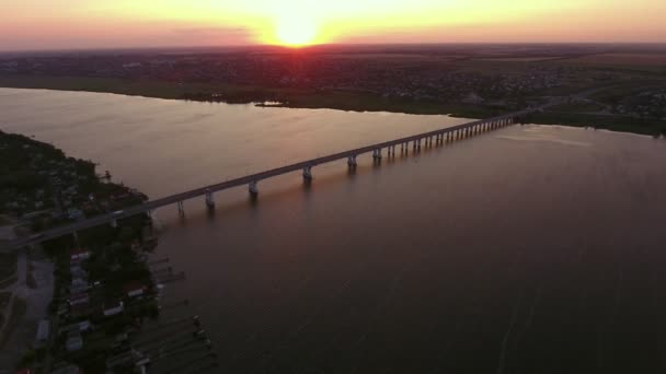 Vue aérienne d'un pont à cordes au-dessus du Dnipro au coucher du soleil surréaliste en été Vue aérienne rêveuse d'un pont de grande envergure au-dessus de la rivière Dnipro avec des berges sombres, des voitures et de l'eau scintillante à un magnifique coucher de soleil en été 