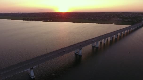 在夏季梦幻般的日落时分 在Dnipro河上的一座远处的桥梁的空中拍摄 在夏天的夕阳下 在Dnipro河上 一座伸出的今天桥被伸出的桥架上 在黑暗的河岸上行驶 在闪闪发光的日落中闪闪发光 — 图库视频影像