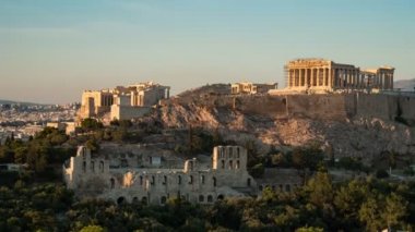 Atina Akropolis yaz aylarında altın görünümlü duvarları ile bir timelapse çekim olarak Atina Akropolis ciddi sütunlar ve altın görünümlü duvarlar ile görkemli sütunlar ve altın görünümlü duvarlar ile gündüzden yaz aylarında geceye kadar pitoresk gün batımında